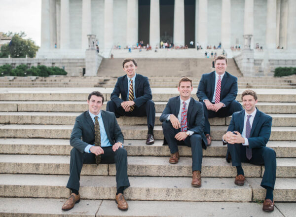 group of brothers in suits sitting on stairs