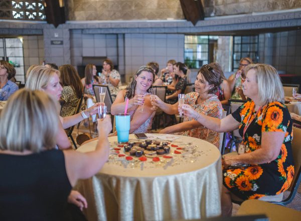 a group of women toasting around a table