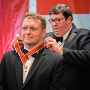 Knight Commander Simmons placing Knight Commander's Accolade around neck of Trey Horne
