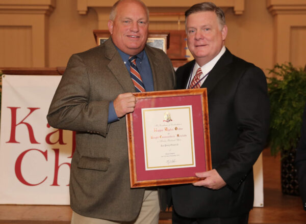 Knight Commander Aiken posing with Lee Oliver and framed award certificate