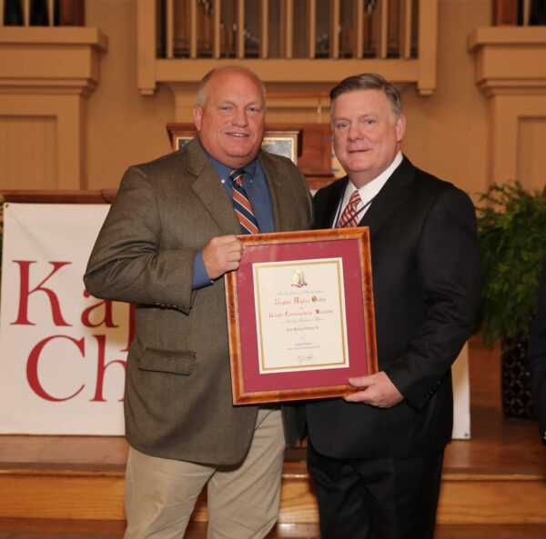 Knight Commander Aiken posing with Lee Oliver and framed award certificate