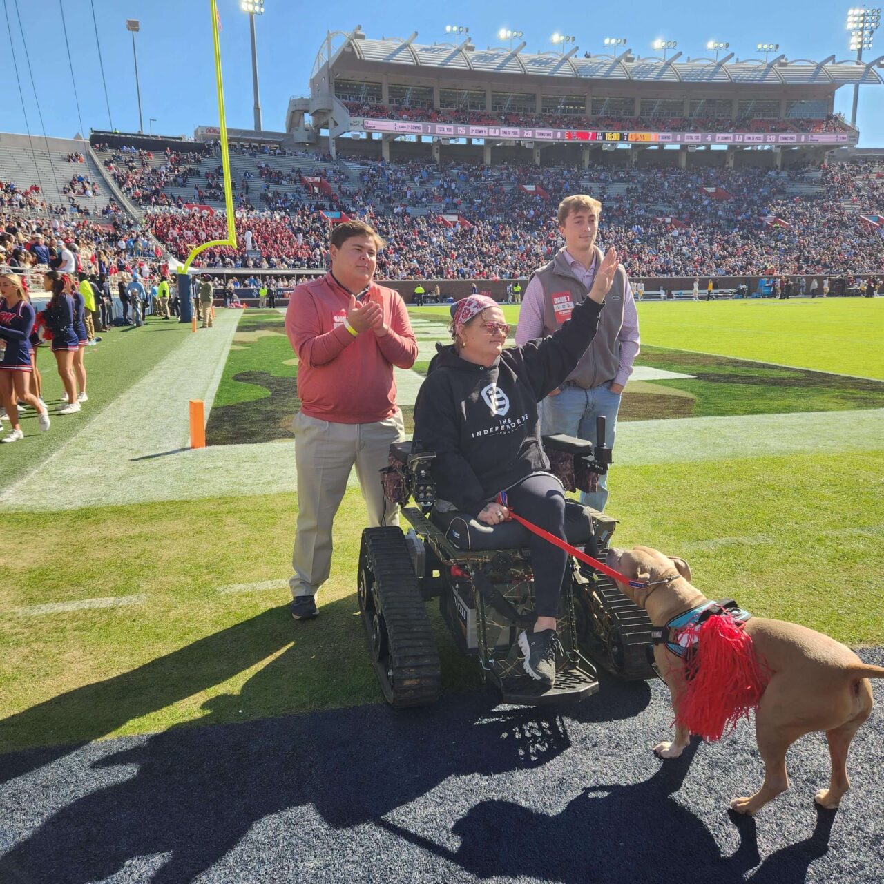 Brooks standing, Hutchinson in track chair, Marks, and dog pork chop on the football field