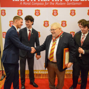 Tom Murray shaking hands with Zeta Omicron undergraduate