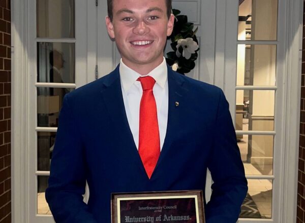 young man in suit holding award