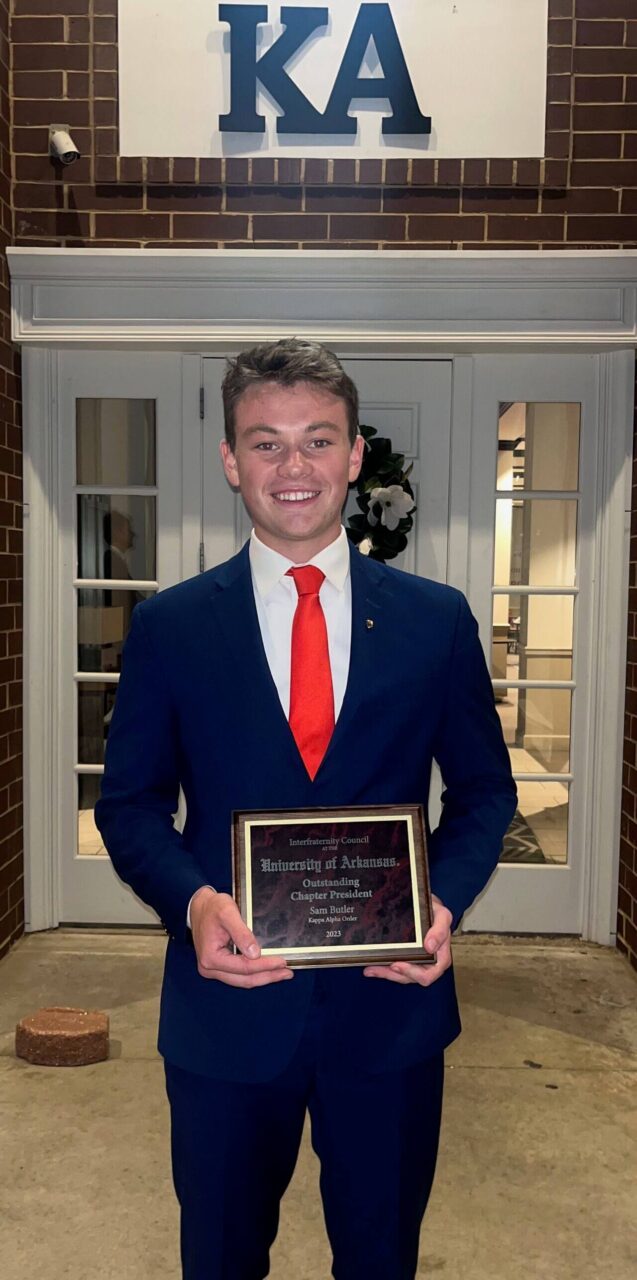 young man in suit holding award