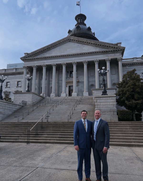 two men in suits in front of statehouse