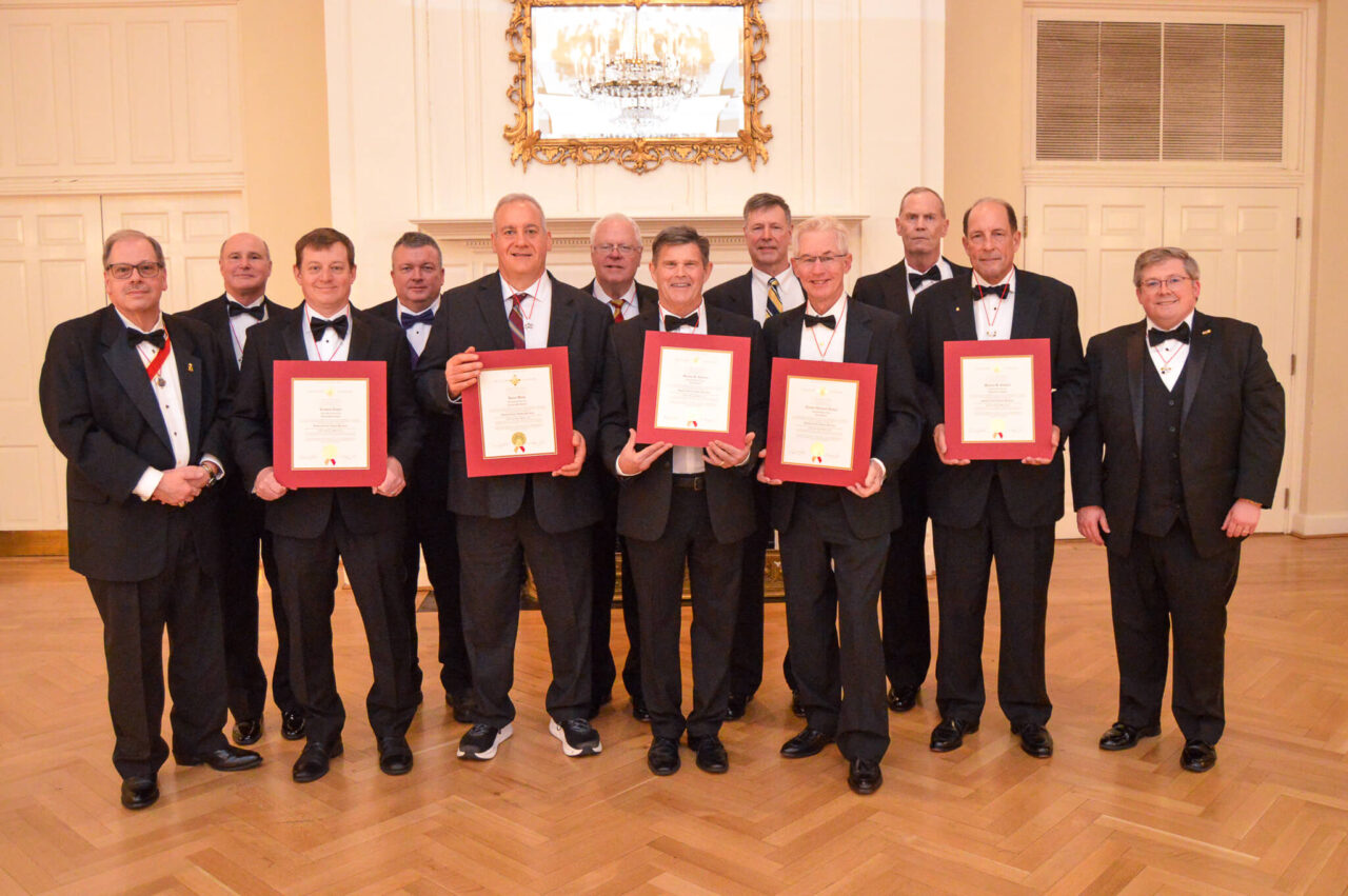 group of men in tuxes holding certificates