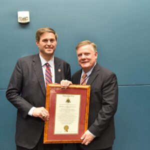 two men in suits holding framed certificate