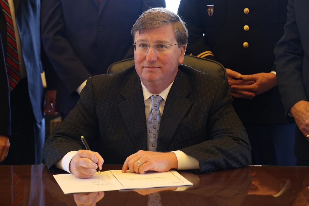 man at desk signing paper