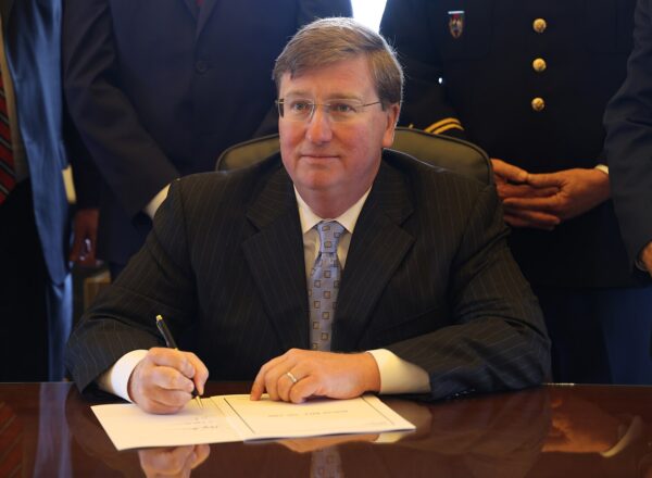 man at desk signing paper
