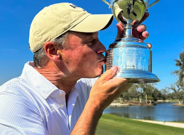 man in golf hat and polo kissing golf trophy