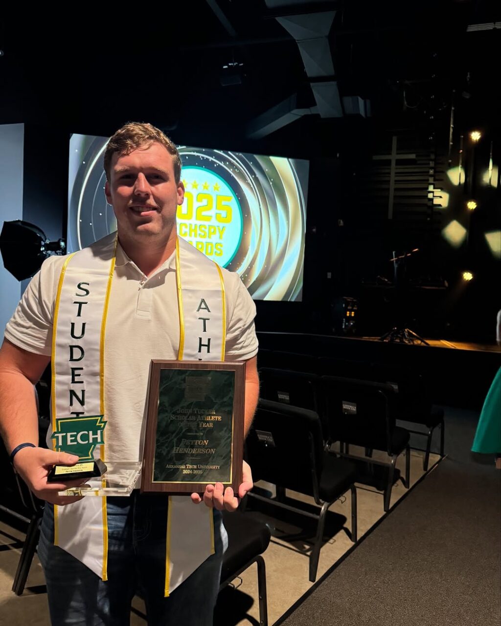 young man wearing a stole and holding awards