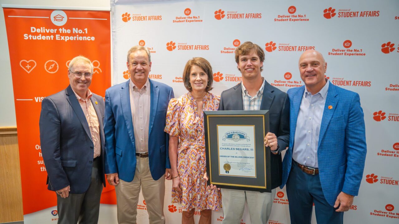 family with young man holding framed award