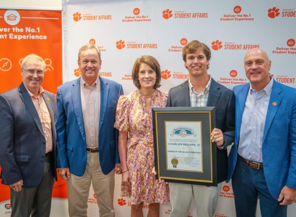 family with young man holding framed award
