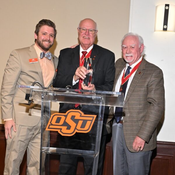 men in suits at podium. middle holding award.